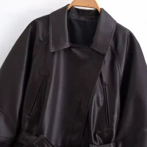 Black faux leather trench coat detail shot showing lapel collar, buttons and smooth texture.