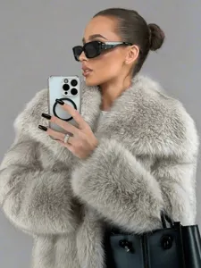 Detail shot of a stylish faux fur lapel coat in a chic mirror selfie scene, soft texture.