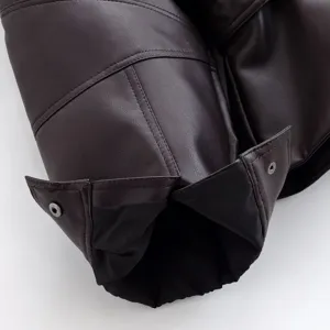 Close-up of women's short faux leather jacket sleeve with button and lining details.