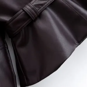 Close-up detail of women's short leather jacket featuring belt loop and fine stitching.