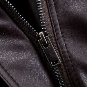 Close-up detail of dark brown leather jacket zipper, smooth metal pull and neat stitching.