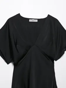 Close up view of elegant black V-neck satin dress collar detail showcasing short dolman sleeves.