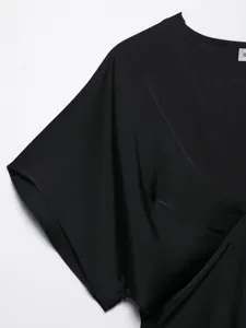 Detailed view of the black satin V-neck short sleeve top showing fine fabric texture.