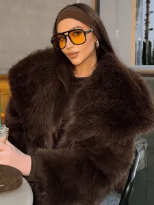 Detail shot of the stylish brown faux fur jacket worn by a model in a chic cafe setting.