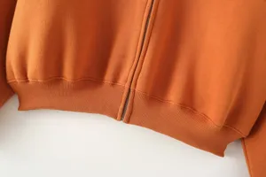 Close up view of women orange zip up hoodie jacket hem and zipper detail, comfortable fabric.