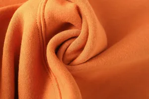 Close-up fabric detail of orange sweatshirt, soft texture, neat stitching, high quality.