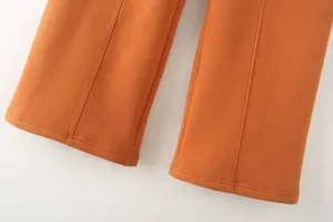 Orange trousers detail view, casual pants hem and clean front seam close-up presentation.