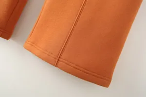 Close-up detail view of vibrant orange casual pants fabric showcasing neat stitching craft.