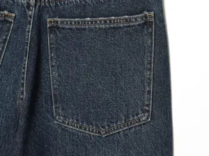 Primo piano sui dettagli dei jeans in denim blu scuro con cuciture gialle a contrasto e tasca.