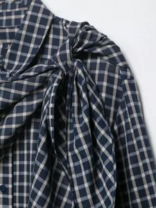 Detailed view of the stylish navy plaid women's blouse, featuring a chic knotted bow collar.