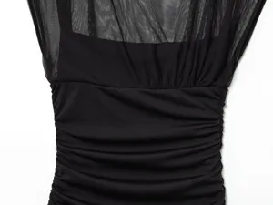Primer plano de patchwork de malla negra y elegantes detalles fruncidos en vestido sin mangas.