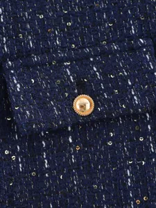 Close-up detail of a dark blue tweed jacket showing metallic sequins and a gold button.