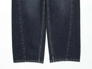 Primo piano di jeans in denim scuro con cuciture doppie a contrasto e dettagli di pannelli.