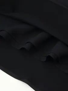 Close-up detail of smooth black satin fabric garment, featuring fine stitching and pleats.