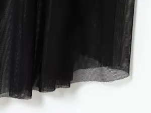 Detalle de tela de malla negra de vestido de mujer con textura plisada fina y transparente.