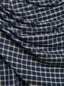 Close-up detail of navy blue and white plaid fabric showing soft texture and natural draping folds.