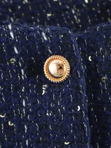 Close-up of navy blue tweed fabric jacket with metallic gold threads and a textured button.