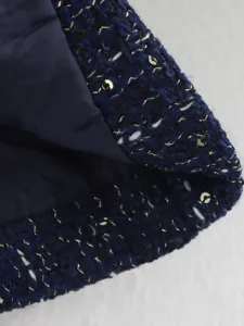 Navy blue tweed jacket detail shot with metallic gold threads and sequins. Premium texture.