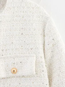 White tweed jacket detail shot featuring gold threads, pocket and stylish metal button design.