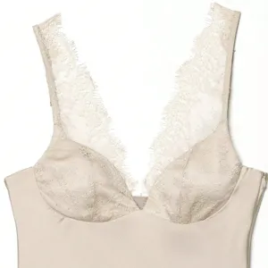 Close-up detail of elegant champagne satin camisole featuring delicate floral lace V-neck trim.