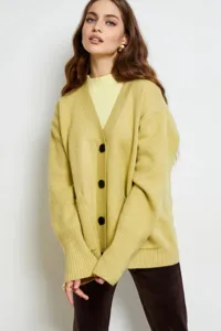 Detalle en primer plano del cárdigan de punto amarillo con cuello en V y botones negros.