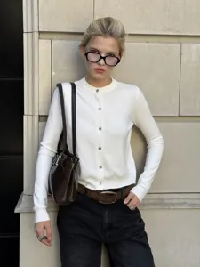 Szenendetail einer weißen Damen Strickjacke mit Knöpfen und klassischem Rundhalsausschnitt.
