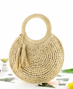 Vista dettagliata della borsa rotonda in paglia intrecciata con eleganti nappe per la spiaggia.