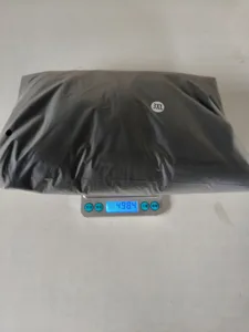 Detail view of packaged clothing outfit in size 3XL weighed on an electronic scale.