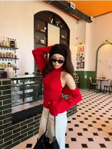 Detail view of the red cold-shoulder knit sweater with chic halter design and stylish shawl.