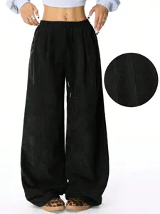 Close-up detail of soft black corduroy wide-leg trousers fabric texture and draped casual style.