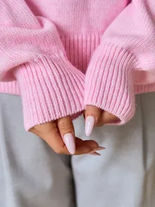 Primer plano detallado de la manga del jersey de punto rosa, tela suave y puños acanalados.