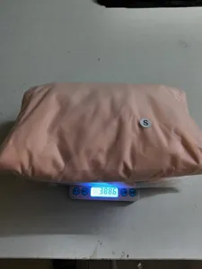 Detailed view of packaged casual knitwear on electronic scale showing weight in warehouse setting.