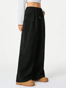 Detail view of the high-waisted black corduroy wide-leg pants showing texture and drawstring.