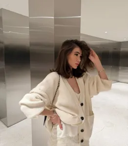 Detailed lifestyle shot of an off-white oversized knit cardigan paired with a chic dress.