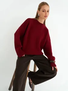 Vista dettagliata di un morbido maglione bordeaux con vestibilità rilassata e coste.