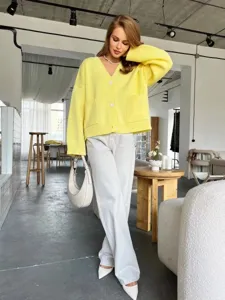 Vista detallada de un cárdigan de punto amarillo acogedor con cuello en V en loft moderno.