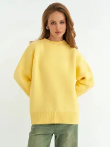 Dettaglio maglione in maglia gialla, vestibilità comoda, tessuto morbido, abbigliamento.
