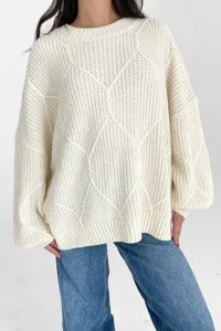 Nahaufnahme des kuscheligen beige Strickpullovers mit stilvollem Rautenmuster Detail.