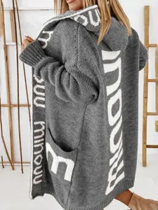 Detailansicht des grauen oversize Kapuzen-Strickjacke mit auffälligem Buchstabenmuster.