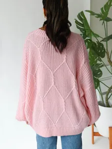 Rückseitenansicht eines rosa Zopfstrick Oversize Damen Pullovers für gemütliche Mode.