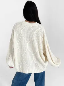 Detailansicht eines gemütlichen, beigen Oversize-Strickpullovers mit stilvollem Rautenmuster.