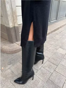 Dettaglio dell'abito in maglia nera con spacco laterale e stivali alti molto eleganti.