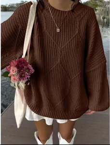 Nahaufnahme des braunen Oversize-Zopfmuster-Pullovers, zeigt Textur und schöne Stegansicht.