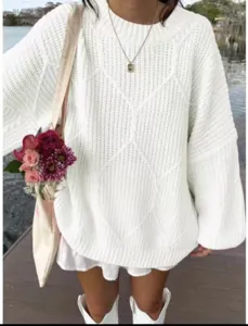 Nahaufnahme eines weissen Oversize Zopfmuster Pullovers mit Rautenstruktur im Freien.