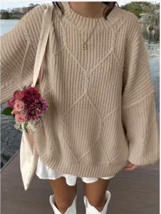 Detailaufnahme des kuscheligen beige Zopfmuster-Pullovers, weicher Stoff, lässiger Look.