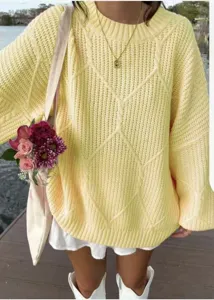 Detailaufnahme des gemütlichen gelben Zopfmuster-Pullovers im Freien, Textur sichtbar.