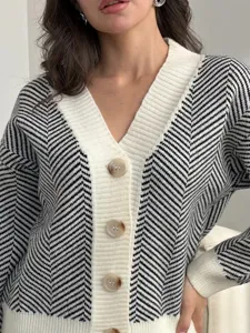 Gedetailleerd overzicht van zwart-witte chevron gebreid vest met V-hals en knopen.