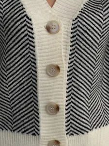Gebreid cardigan trui detailweergave, zwart-witte chevron patroon, geribbelde sluiting.