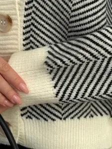 Close-up detail van de zwart-witte chevron gebreide vest mouw textuur en knopen voor dames.
