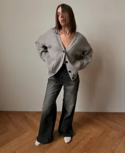 Detailed shot of a cozy gray V-button cardigan sweater worn by model with wide pants.